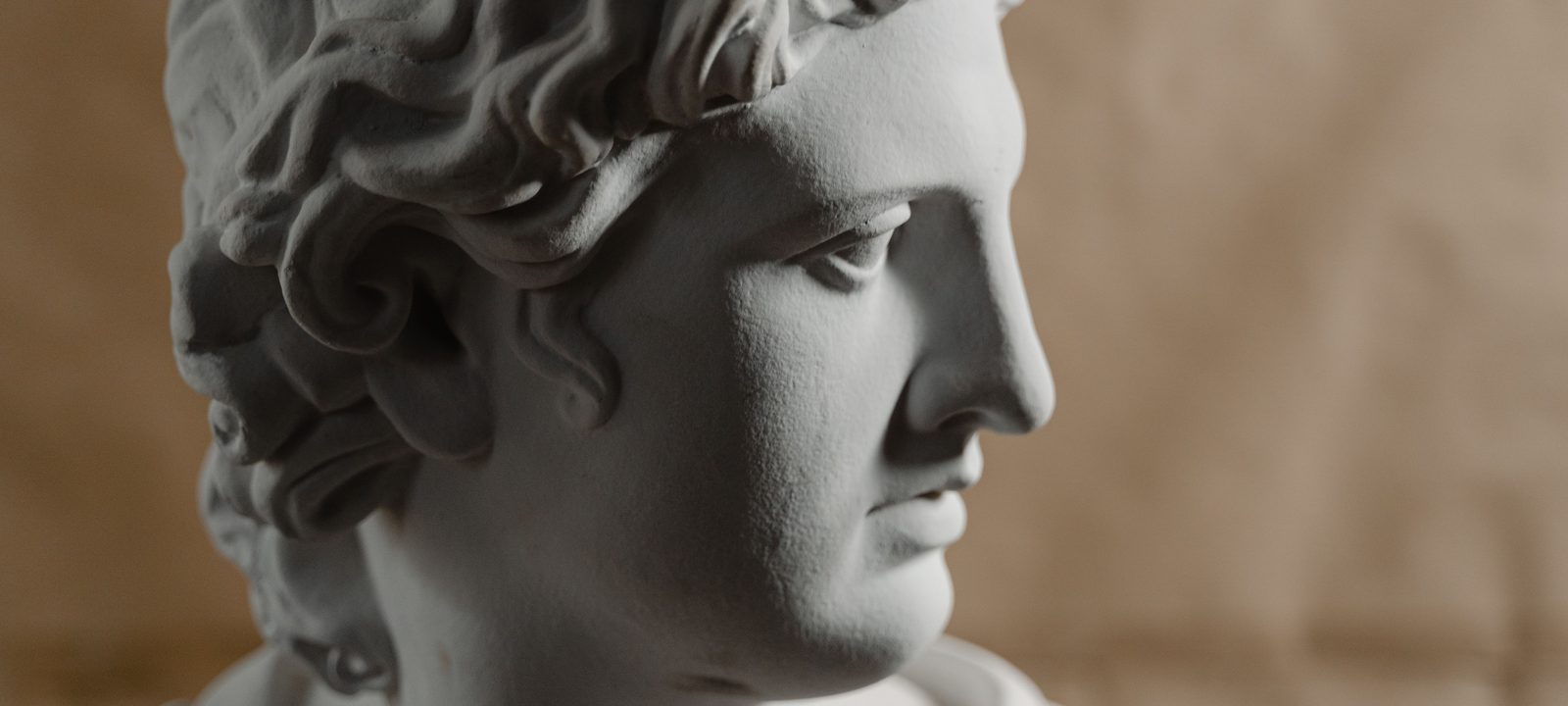 Close-up of a classical marble bust on a soft brown background, artistic lighting.