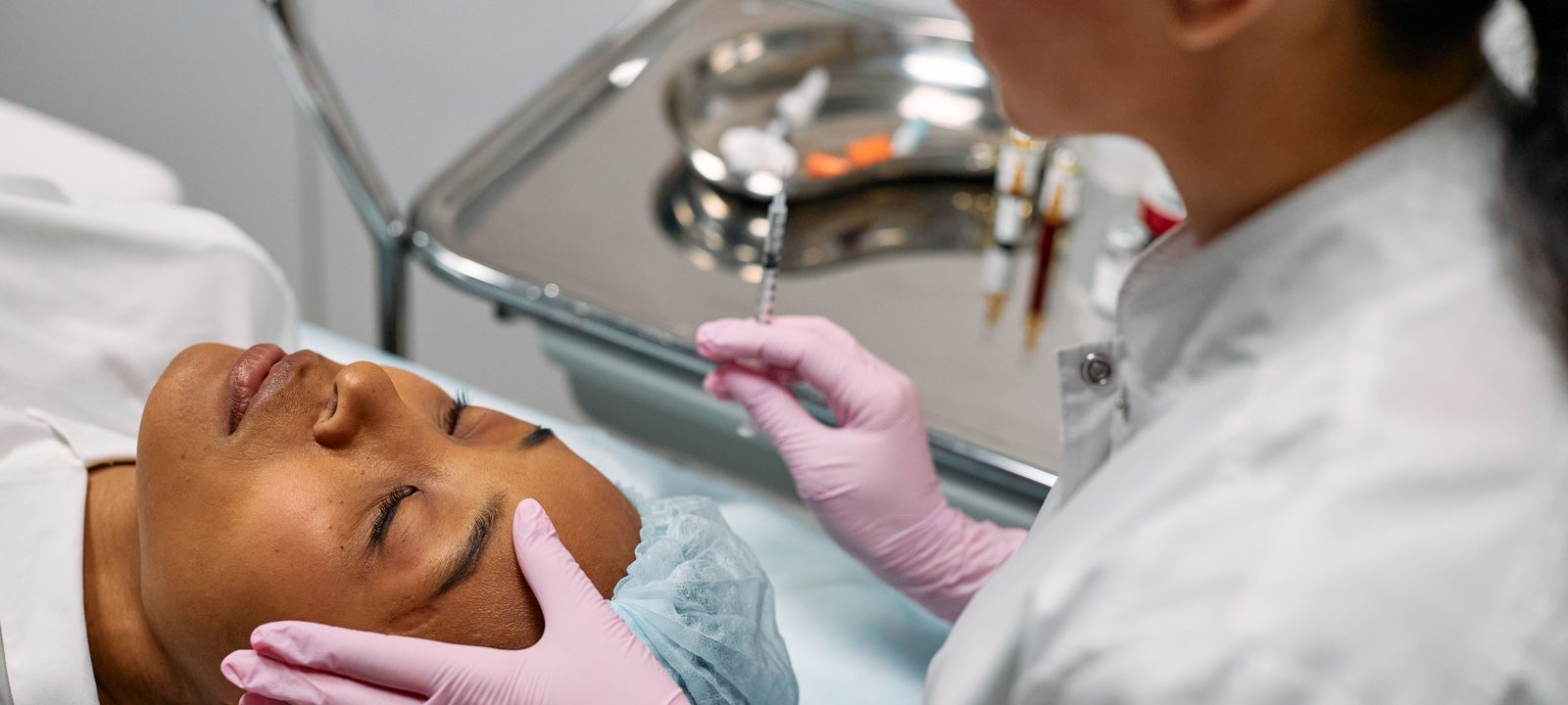 Professional administering skincare treatment with syringe indoors.