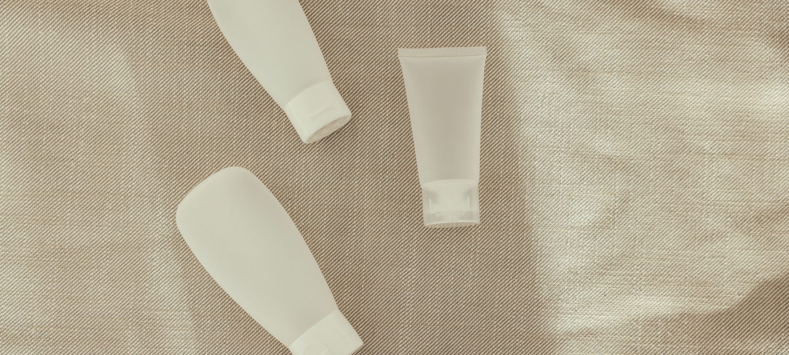 Flat lay image of minimalist plastic squeeze bottles on a textured surface.