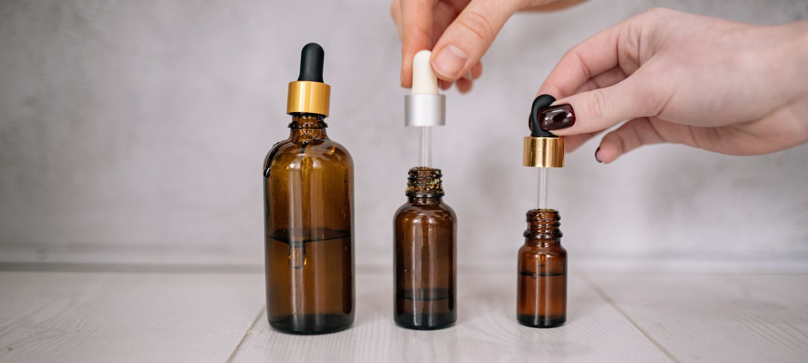 Close-up shot of hands holding brown bottles with droppers, ideal for skincare and aromatherapy themes.